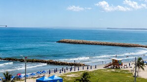 A beach with a lifeguard tower, umbrellas, and a rocky breakwater. -  Hotel Azure Cartagena (Cartagena)