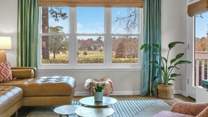 A room with a large window, a sofa, a small table, and a potted plant. - Sea Trail Condo with Golf, Pools, Tennis & Beach Access (Sunset Beach)