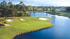 A golf course with bunkers, a water hazard, and a flagstick. - Sea Trail Condo with Golf, Pools, Tennis & Beach Access (Sunset Beach)