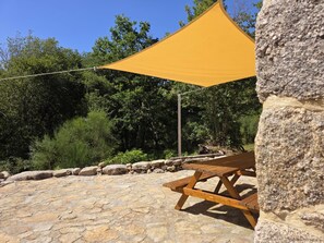 A stone patio with a wooden picnic table and a yellow shade sail. - Coração de Dorna House | Castro Laboreiro | Peneda-Gerês National Park (Castro Laboreiro)