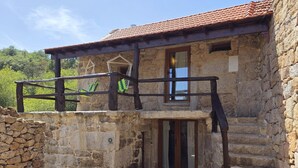 A stone building with a balcony, a wooden staircase, and a door with glass panels. - Coração de Dorna House | Castro Laboreiro | Peneda-Gerês National Park (Castro Laboreiro)