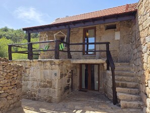 A stone building with a balcony, a wooden staircase, and a door with glass panels. - Coração de Dorna House | Castro Laboreiro | Peneda-Gerês National Park (Castro Laboreiro)