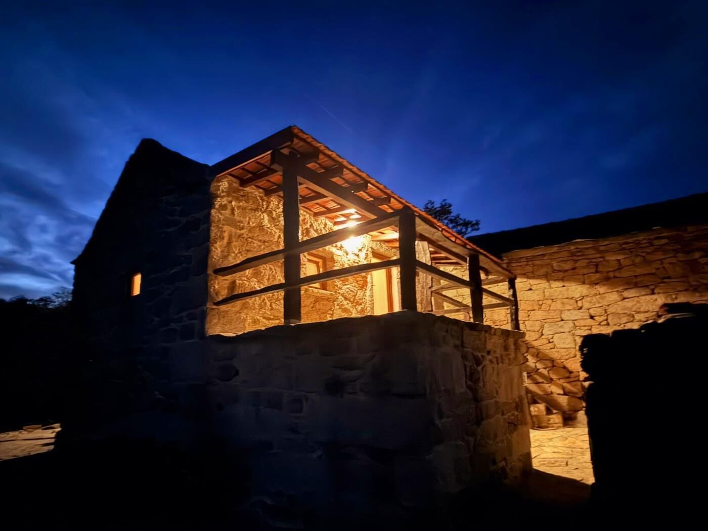 A stone building with a wooden structure on top, possibly a guesthouse or lodge, with a clear sky in the background.