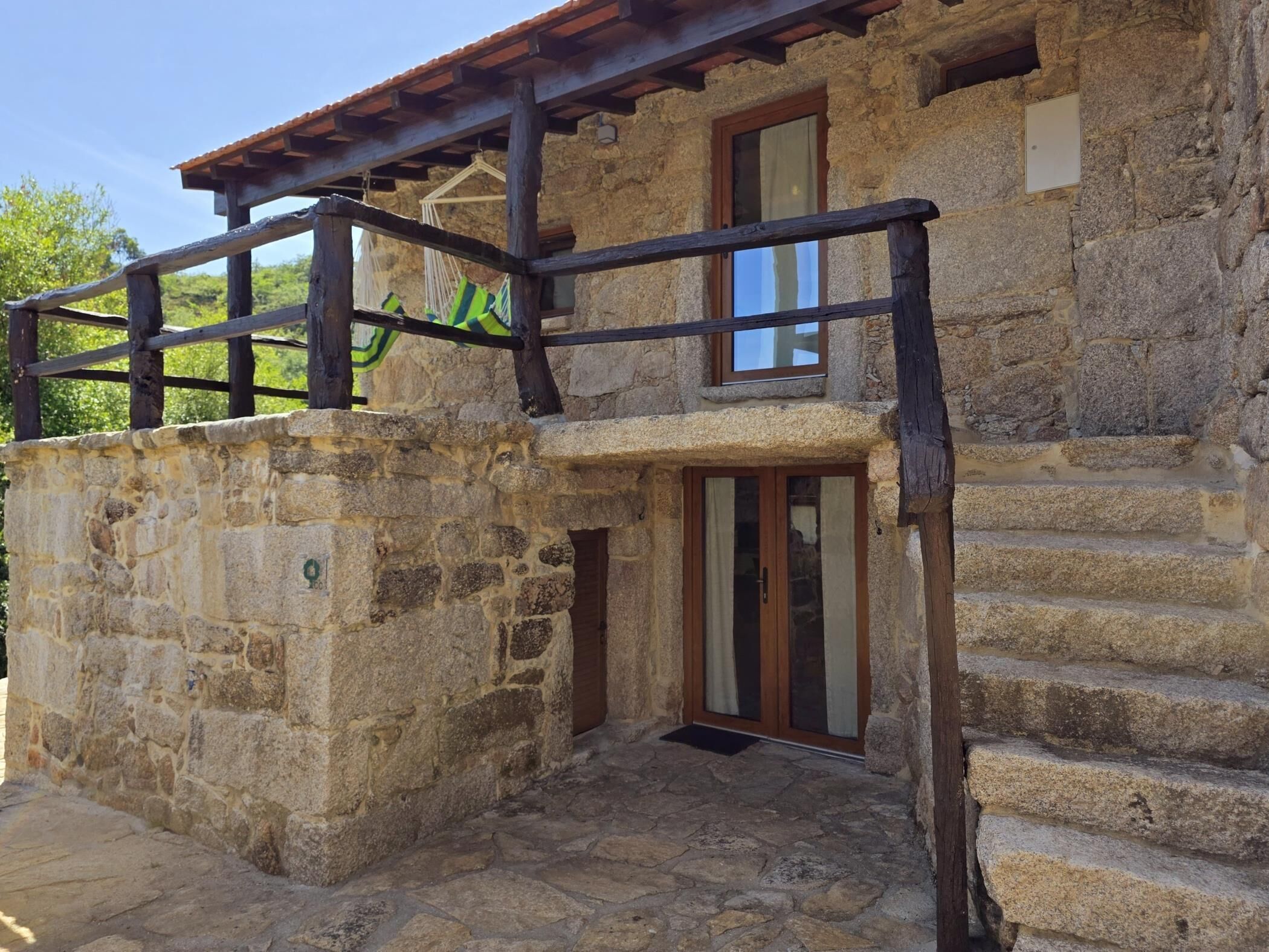 Ein Steinhaus mit einem Holzbalkon, einer Tür und einem Fenster.
