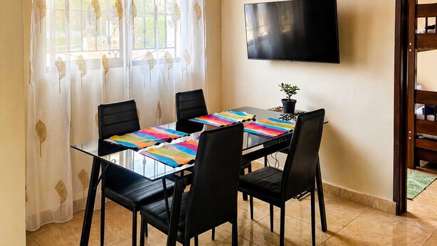 Un espace repas doté d’un plafond en bois, d’un téléviseur fixé au mur et d’une table avec des chaises.