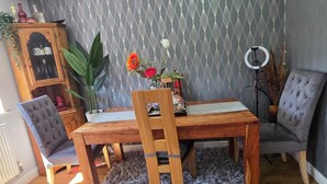 A dining area with a wooden table and chairs, a patterned wallpaper, and a radiator. - Spacious 2 bedroom maisonette (Broughton)