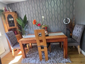 Ein Essbereich mit einem Holztisch und Stühlen, einer gemusterten Tapete und einer Heizung.