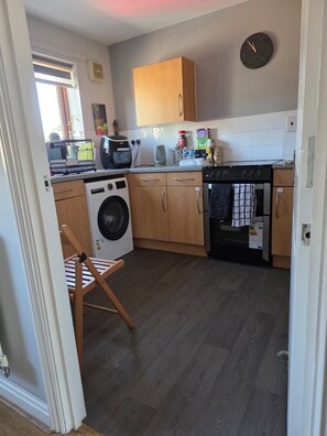 Eine kleine Küche mit Waschmaschine, Backofen und Holzschränken.