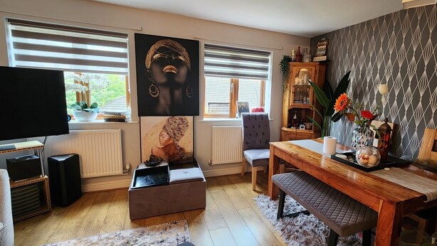 A living room with a TV, a sofa, a wooden dining table, and a bookshelf. - Spacious 2 bedroom maisonette (Broughton)