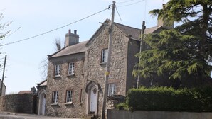 Un bâtiment en pierre à l’architecture traditionnelle, doté d’une porte d’entrée centrale, de nombreuses fenêtres et d’une cheminée.