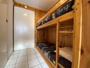 Una habitación con literas, una puerta y suelo de baldosas.