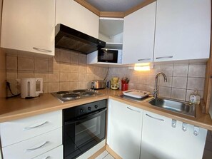 A compact kitchen with a stove, oven, microwave, and sink. - 3rd floor, balcony, tv, ski locker, 20m², Praz sur Arly (Praz-sur-Arly)