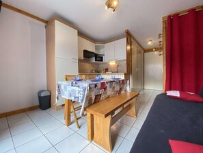 A compact room with a dining table, a bench, a bed, and a kitchenette. - 3rd floor, balcony, tv, ski locker, 20m², Praz sur Arly (Praz-sur-Arly)