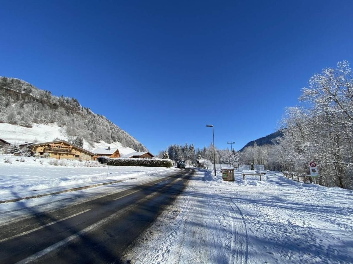 A snow-covered road with buildings on the left and a mountain in the background.