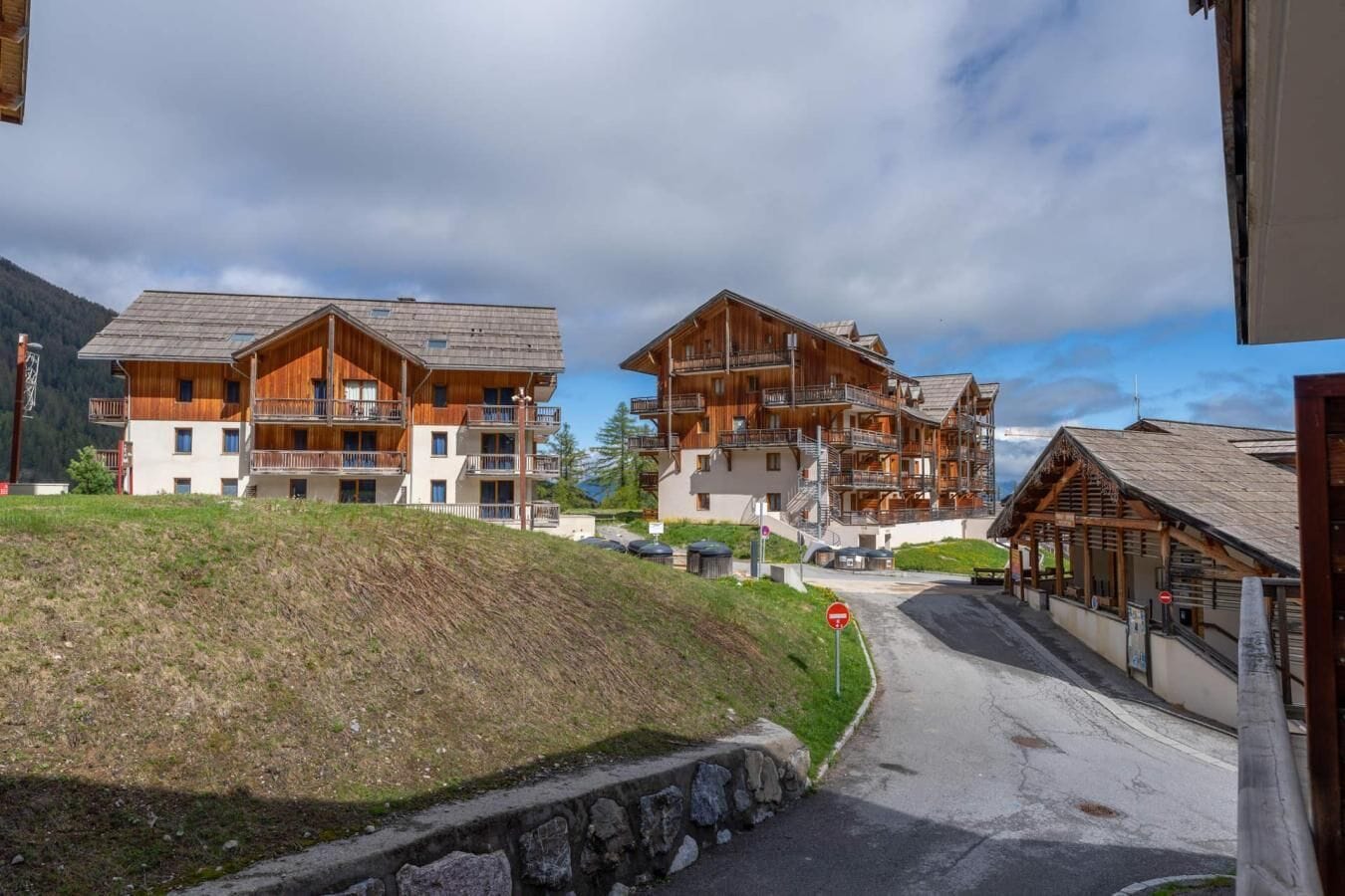 A multi-story hotel with balconies, a stone retaining wall, and a clear sky.
