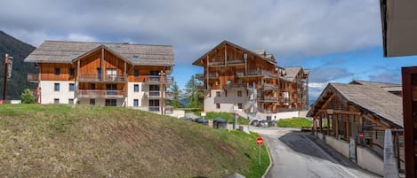 A multi-story hotel with balconies, a stone retaining wall, and a clear sky.