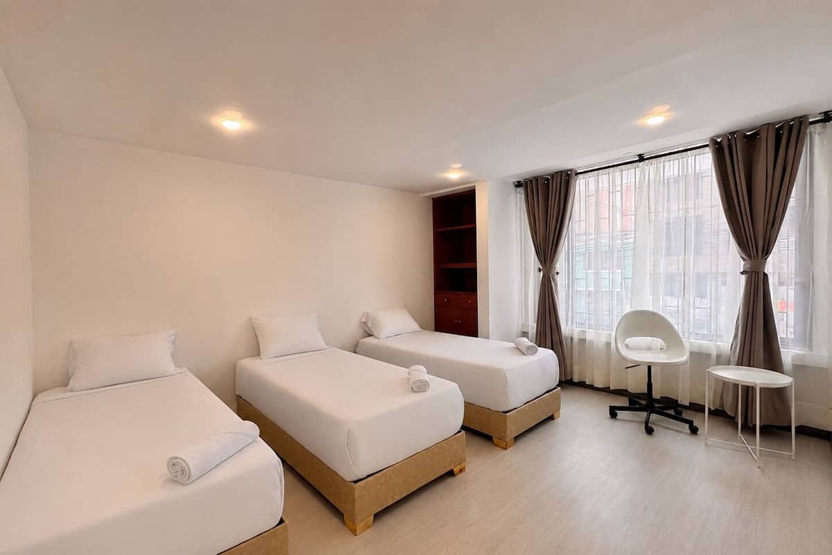 A hotel room with two single beds, a desk, and a chair.