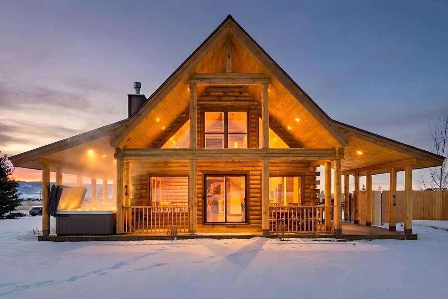 A log cabin with a large porch, a chimney, and a snow-covered ground.