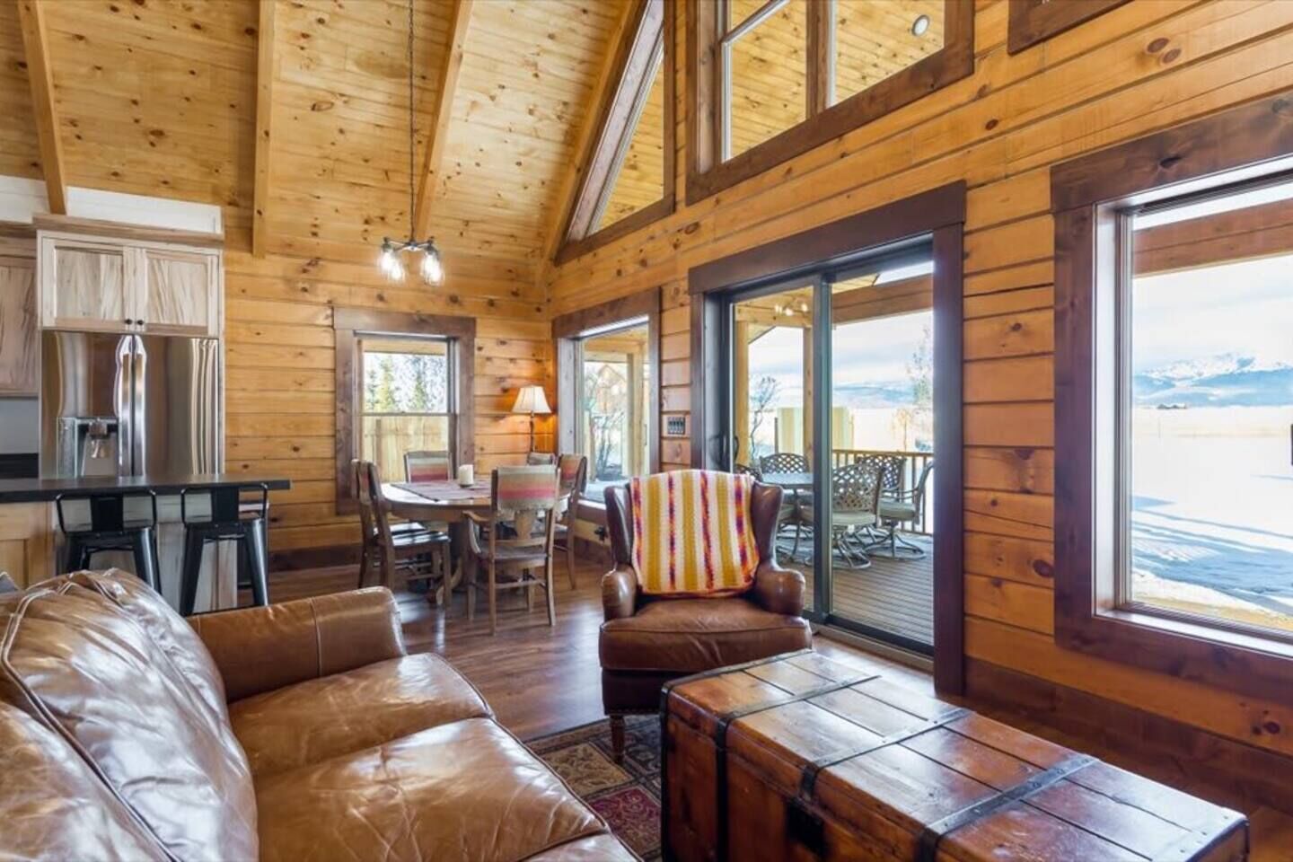 A cabin interior with a dining area, a sofa, a chair, and a table.