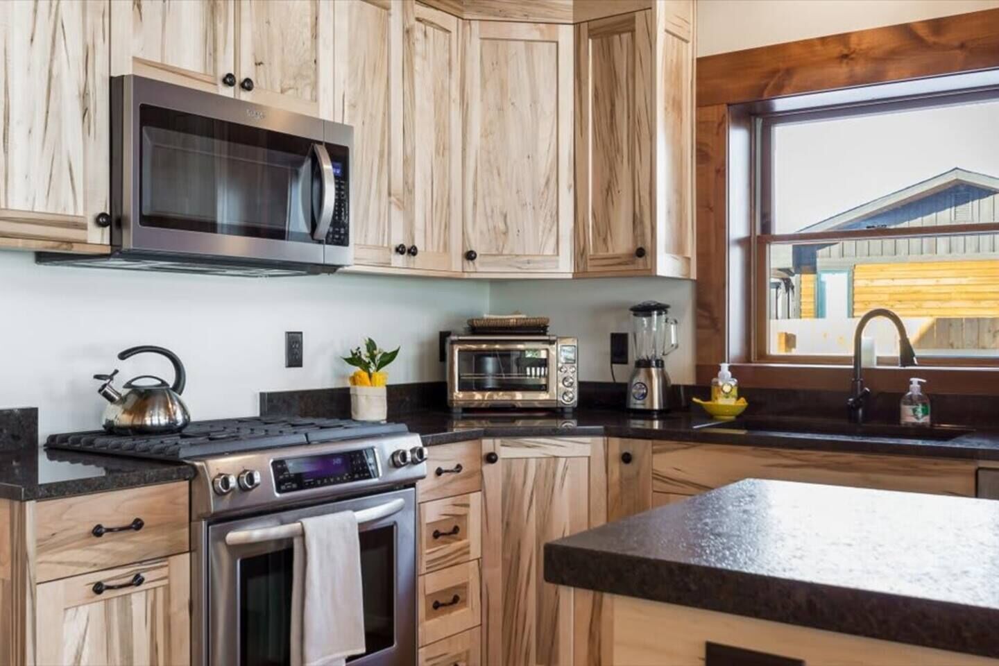 A kitchen with wooden cabinets, a microwave, a stove, a toaster, and a blender.