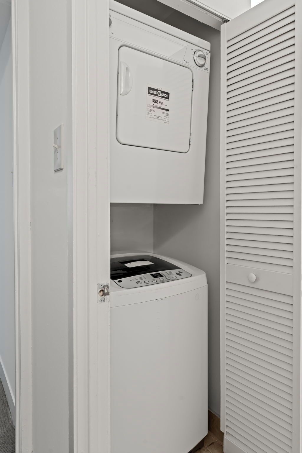 A compact, white laundry room with a washing machine and dryer, a door with a handle, and a small window.