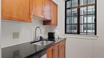 A kitchen with wooden cabinets, a stainless steel sink, and a window with a view of buildings.