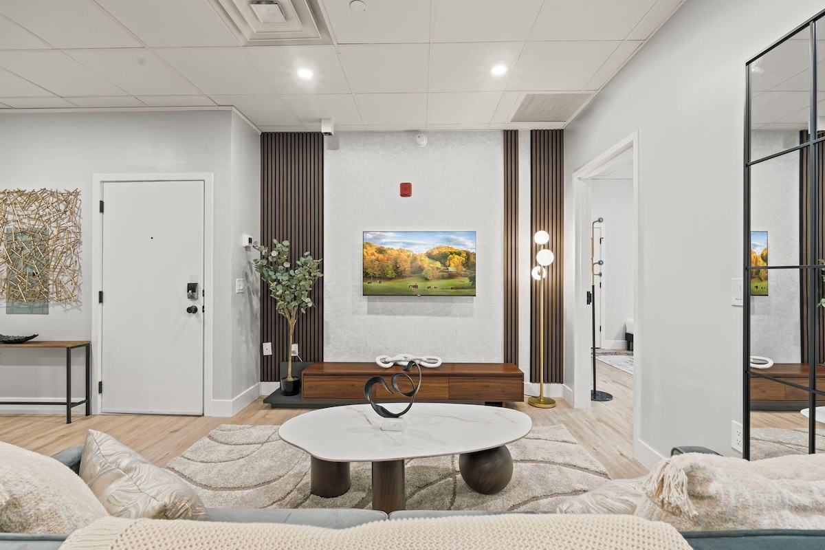 Ein modernes Wohnzimmer mit einem runden Tisch, einer Bank und einem großen Gemälde an der Wand.