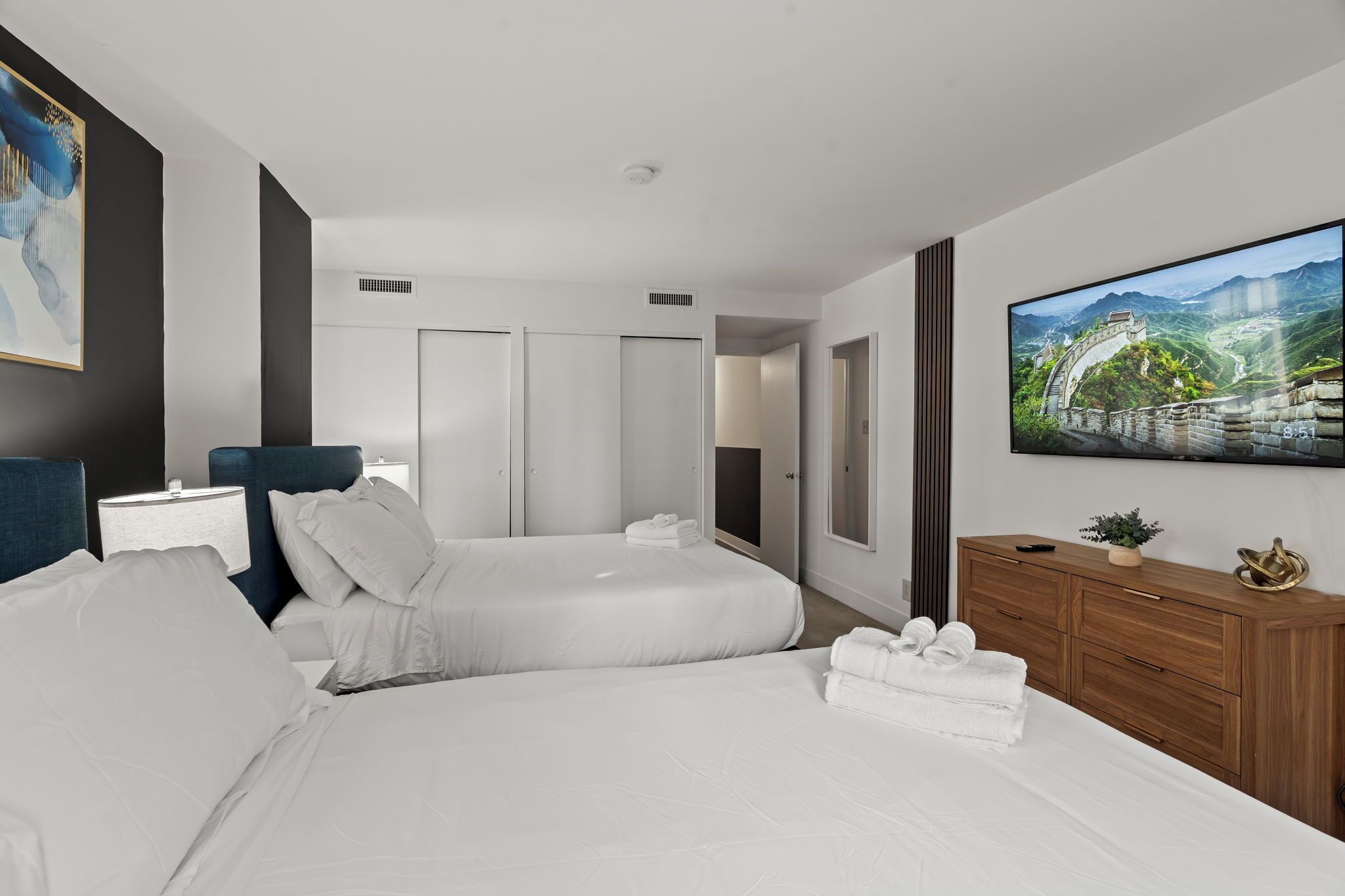 Camera d'albergo con un grande letto, una TV a parete e un comò in legno.