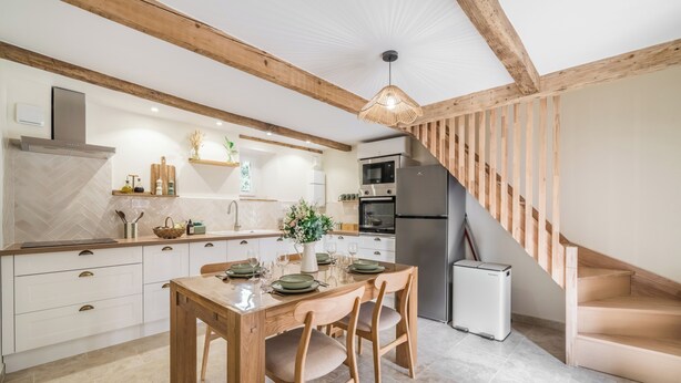 A modern kitchen with wooden beams, a dining table set for four, and a built-in oven. - A Getaway to Les Granges: River 200 meters away on foot (Saint-Martin-d'Ardèche)