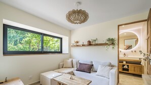 A modern living room with a sofa, a coffee table, a large window, and a wooden cabinet with a mirror. - A Getaway to Les Granges: River 200 meters away on foot (Saint-Martin-d'Ardèche)