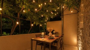 An outdoor dining area with a table set for two, surrounded by chairs, under string lights and a tree. - A Getaway to Les Granges: River 200 meters away on foot (Saint-Martin-d'Ardèche)