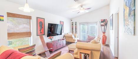 A living room with a sofa, a coffee table, a TV, and artwork on the walls.