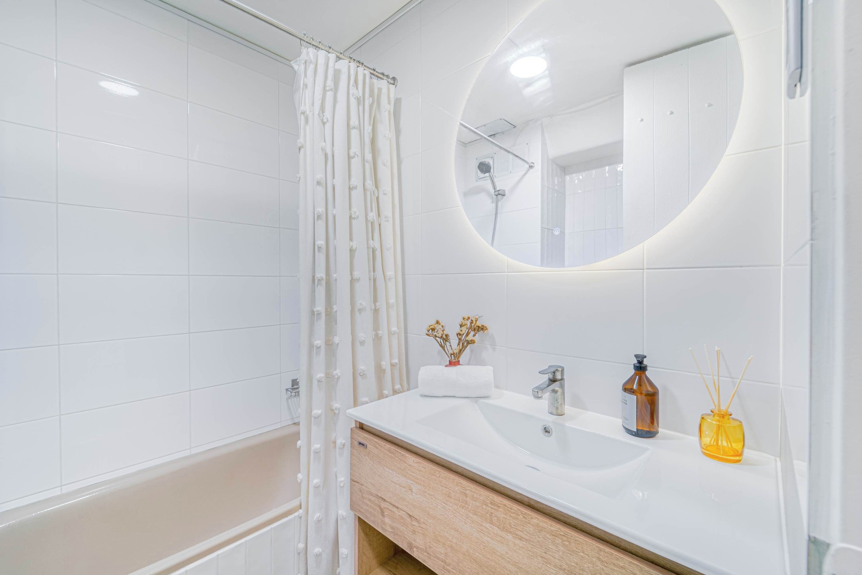 Une salle de bain moderne avec un lavabo blanc, un miroir et une douche.