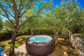 Un jacuzzi en un jardín con árboles y una terraza de madera.