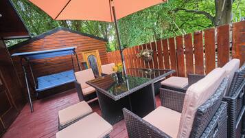 An outdoor patio with wicker furniture, a glass-top table, and a swing seat.
