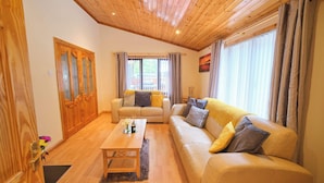 A living room with a wooden ceiling, a sofa set, a coffee table, and a window with curtains.