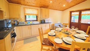 A wooden kitchen with a dining area, featuring cabinets, a stove, and a table set for four.
