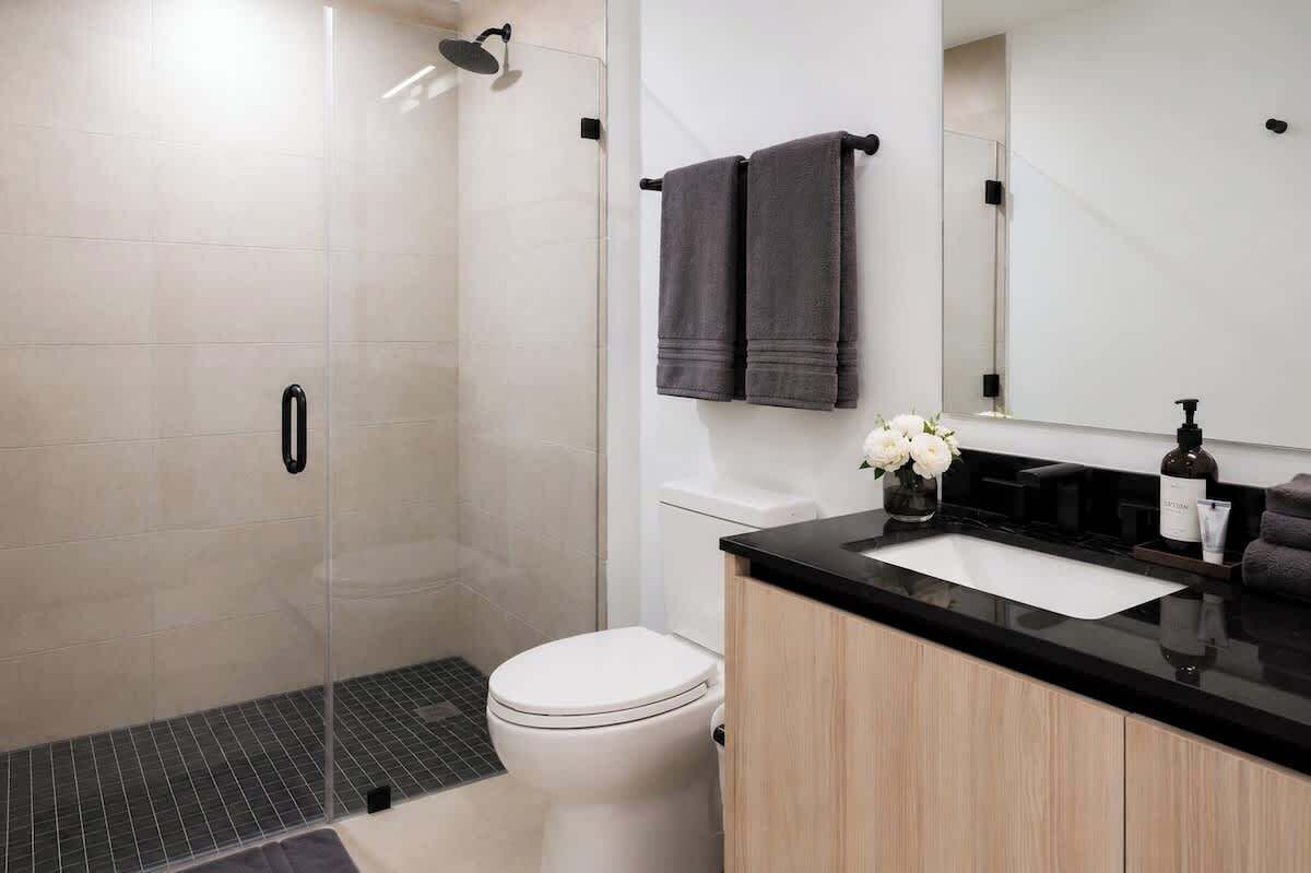Ein modernes Badezimmer mit Dusche, WC und Waschtisch inklusive Spüle und Spiegel.