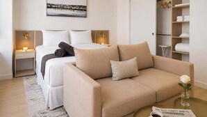 Quarto de hotel com cama, sofá, mesa de cabeceira, armário e vista para uma paisagem nevada.