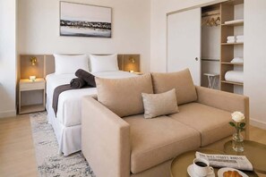 A hotel room with a bed, a sofa, a nightstand, a bedside table, a closet, and a view of a snowy landscape. - Prime Miami Luxury Unit | King Bed | Sleeps 2 (Miami)