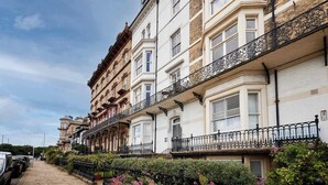 A row of traditional terraced houses with balconies, a paved street, and parked cars. - Host Stay Kingsley House (Saltburn-by-the-Sea)