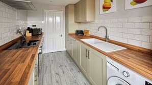 A compact kitchen with a built-in washing machine, a sink, and wooden countertops. - Host Stay Kingsley House (Saltburn-by-the-Sea)