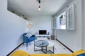 A living room with a sofa, a coffee table, a TV, and a window.