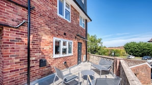 A brick house with a patio, outdoor seating, and a view of the surrounding area. - 3BR Cosy & Chic House, Guildford Festival Offer! (Gulidford)