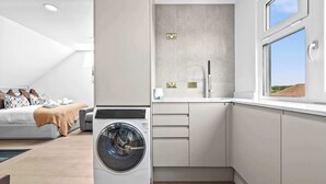 A modern laundry room with a washing machine, a sink, and a window with a view of the landscape. - 3BR Cosy & Chic House, Guildford Festival Offer! (Gulidford)