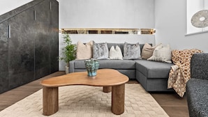 A modern living room with a sectional sofa, a wooden coffee table, and a large cabinet. - 3BR Cosy & Chic House, Guildford Festival Offer! (Gulidford)
