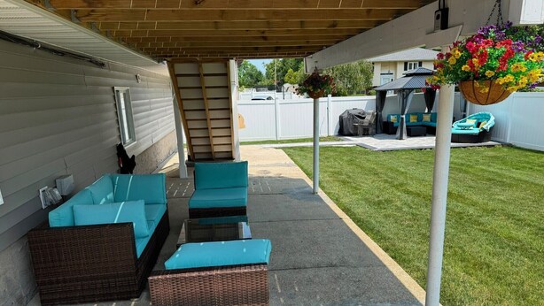An outdoor patio with wicker furniture, a covered area, and a hanging flower basket. - Cozy 1-Bedroom Apartment in Peaceful Commack with Air Conditioning & C. Monoxide (Commack)