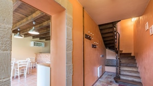 Un couloir avec un escalier, un coin cuisine et un espace repas.