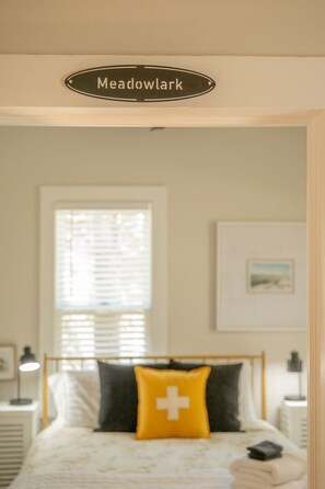 A bedroom with a bed, a bedside table, a nightstand, a window with blinds, and a sign above the bed that reads 'Meadowlark'. - Laid-back, luxurious 4-bed, 2-bath home, 10-minute walk to downtown Saugatuck (Saugatuck)