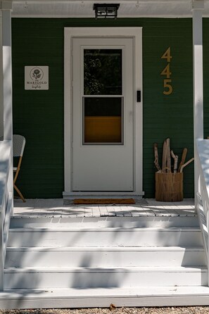 A green house with a white door, steps leading up to the entrance, and a sign on the wall. - Laid-back, luxurious 4-bed, 2-bath home, 10-minute walk to downtown Saugatuck (Saugatuck)